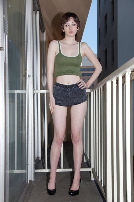 Cute teen girl Lilly Gardner teases fully clothed on the balcony and sofa