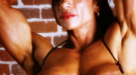 Bodybuilder with tanned body Marina Lopez shows her fakes and poses
