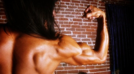 Bodybuilder with tanned body Marina Lopez shows her fakes and poses