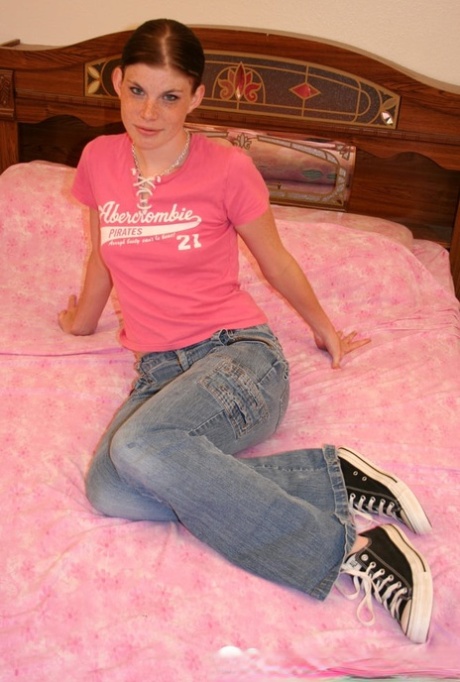 Amateur girl with small breasts undresses and poses on a bed in shoes