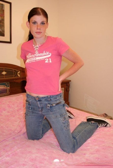 Amateur girl with small breasts undresses and poses on a bed in shoes