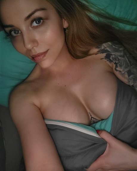 Cute tattooed amateur teases hotly with her covered big tits in her bedroom