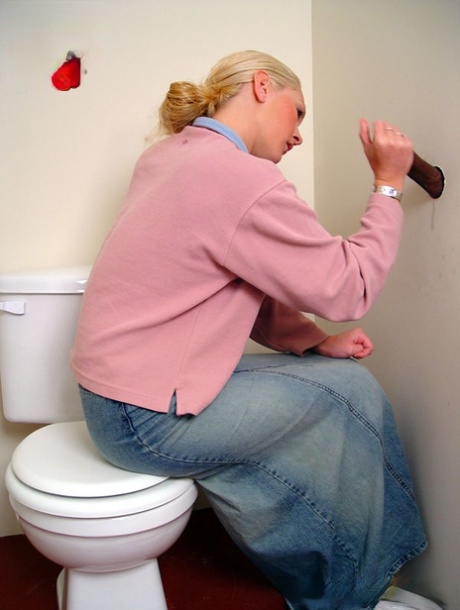 Blonde girl Jamie sits on the toilet and blows a black gloryhole dong